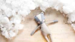 An overhead shot of a Katia Ferris-designed Luckyjuju kitty doll surrounded by fluffy fiberfill. 