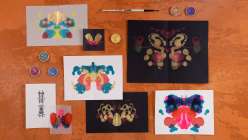 Several images of Rorschach-stye ink blog paintings plus four cakes of metallic watercolor and a watercolor brush.