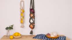Two rope kitchen bags above a table laid with a small vase, three lemons, and an indigo placemat, from Cobrina's Knotted Pantry Bag Creativebug class