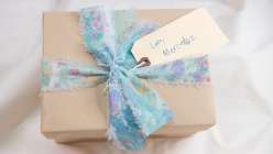 Gift with tag reading Love, Mercedez, wrapped in brown paper and tied in a hand-marbled ribbon from Mercedes Rex's Marbled Gift Wrappings Creativebug class