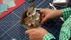 A pair of hands opening up a pop-up card made with paper ephemera from Bel Mills's Make a Pop-Up Flower Greeting Card class on Creativebug