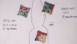Three pattern weights on top of a pre-cut sewing pattern from Rebecca Ringquist's Embroidered Botanical Pattern Weights Creativebug class