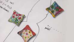 Three pattern weights on top of a pre-cut sewing pattern from Rebecca Ringquist's Embroidered Botanical Pattern Weights Creativebug class