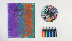 A piece of marbled paper, four marbling inks, and a messy palette from Mercedez Rex's Advanced Marbling Techniques class on Creativebug