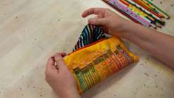 A pair of hands holding an embroidered pencil bag made by Rebecca Ringquist in her Embroidered Pencil Case class on Creativebug