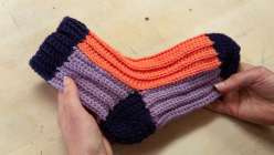 Two hands holding a pair of crocheted ribbed socks from Cal Patch's Crocheted Ribbed Socks class on Creativebug