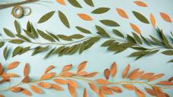 Paper leaves being strung together into a garland in Twinkie Chan's Make Celebration Garlands class on Creativebug