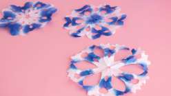 Blue and white paper snowflakes made in Mia Semingson's Make Shibori-Inspired Paper Snowflakes class on Creativebug