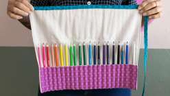 A purple pencil roll full of a rainbow of colored pencils, made in Faith Hale's Sew a Paint Brush and Pencil Roll class on Creativebug.