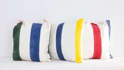 Three white canvas pillows with colorful stripes made in Courtney Cerruti's Painted Canvas Pillows class on Creativebug.
