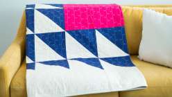Heather Jones demonstrates patchwork quilts by creating a 72-inch square version of the Fly Away quilt block and using a traditional block design on paper, and how to piece quilts together to create a bold, graphic quilt top.